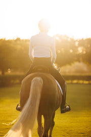 Woman riding a horse into the sunset wearing May Babes riding breeches with built in underwear. Horse is a palomino.